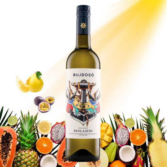 Weinflasche mit dem Etikett 'BUJDOSÓ 2023 SOLARIS' umgeben von verschiedenen tropischen Früchten wie Ananas, Passionsfrucht, Mango, Papaya, Limette, Kokosnuss und Drachenfrucht