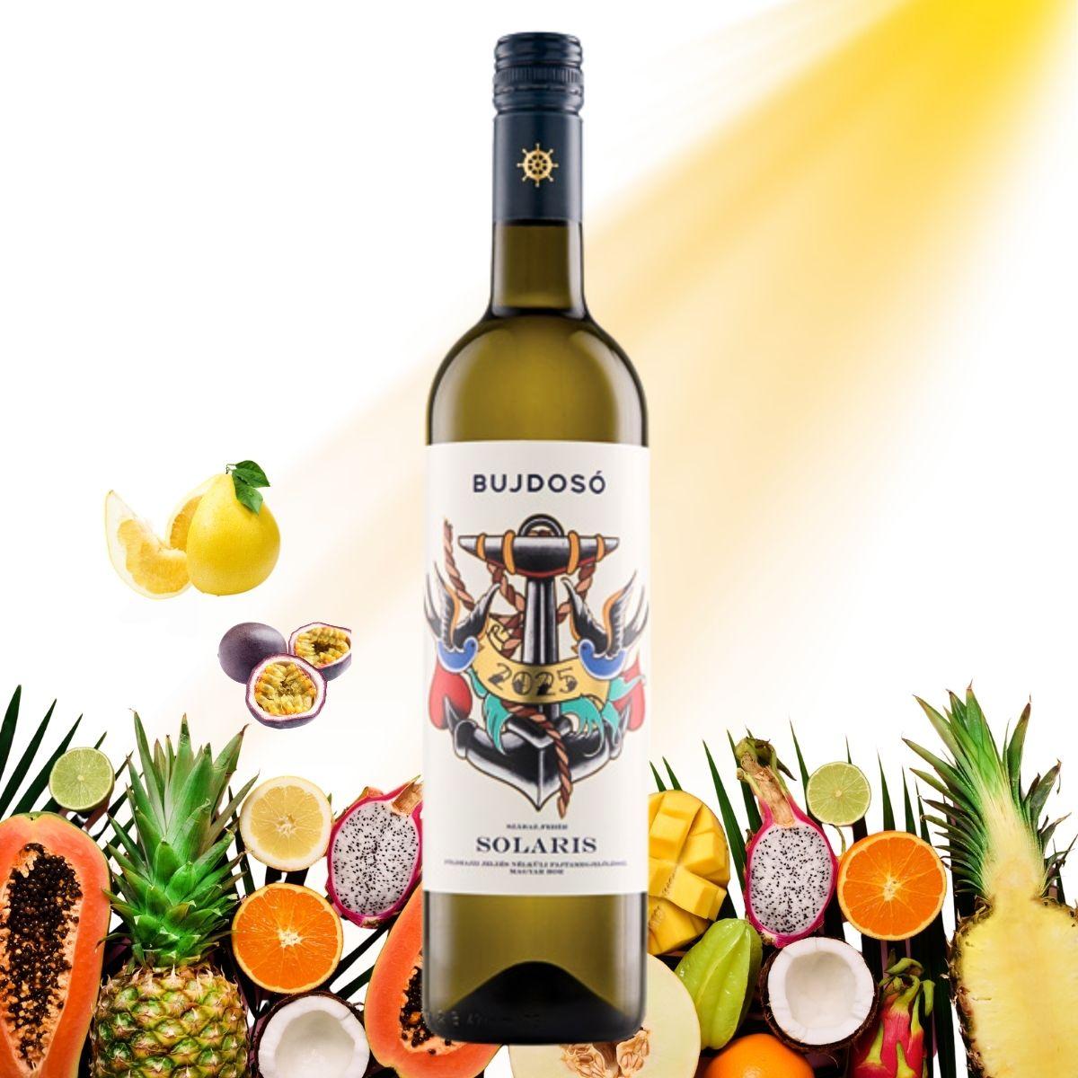 Weinflasche mit dem Etikett 'BUJDOSÓ 2023 SOLARIS' umgeben von verschiedenen tropischen Früchten wie Ananas, Passionsfrucht, Mango, Papaya, Limette, Kokosnuss und Drachenfrucht
