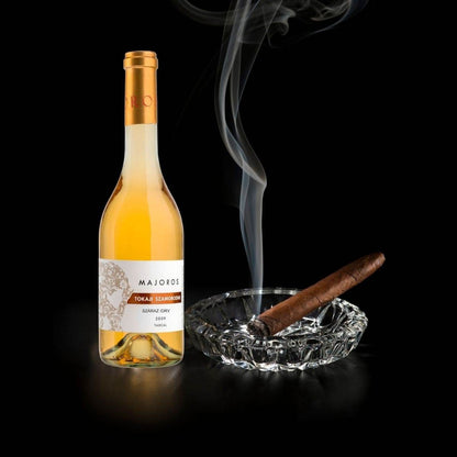 Flasche Majoros Tokaji Szamorodni trockener Weisswein neben brennender Zigarre in klarem Kristallaschenbecher mit Rauch