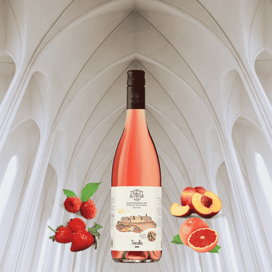 Flasche Roséwein mit Etikett "Pannonhalmi Tricollis" vor weißer, gewölbter Decke, umgeben von Erdbeeren, Himbeeren, Pfirsichhälften und Grapefruit.