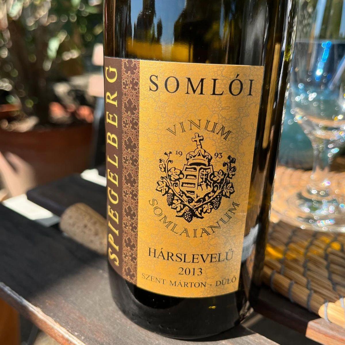 Flasche Spiegelberg Hárslevelű 2013 Weißwein aus Somló mit gelbem Etikett und Wappen, auf Holztisch im Freien